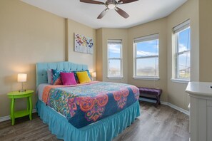Un dormitorio con cama, ventilador de techo, ventana y banco.