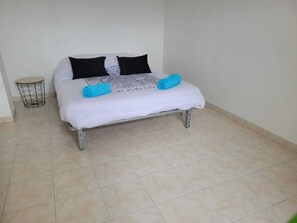 Een bed met een witte matras, twee zwarte kussens en twee blauwe handdoeken.
