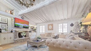 Uma sala de estar ampla com lareira, uma televisão grande e um sofá confortável.