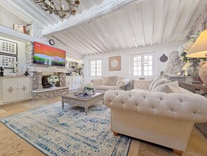 Ein geräumiges Wohnzimmer mit Kamin, großem Fernseher und bequemer Couch.