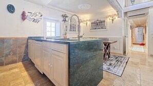 Uma cozinha espaçosa com uma ilha grande, armários brancos e piso de azulejos.