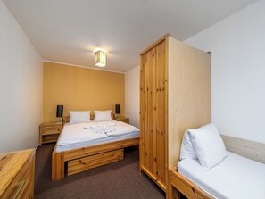 Una habitación con cama, armario de madera, mesita de noche y lámpara.