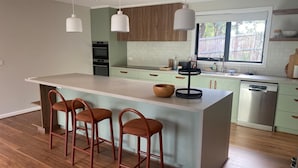 A modern kitchen with a central island, bar stools, wooden flooring, and a dishwasher. - Escape to Nature in Our Warm & Welcoming Family Home (Warrandyte)