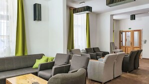 Un moderno vestíbulo de hotel con un sofá, sillones, una mesa de centro de madera y una recepción.