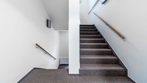 Eine moderne Treppe mit Handlauf, einer Wandleuchte und einem Heizkörper.