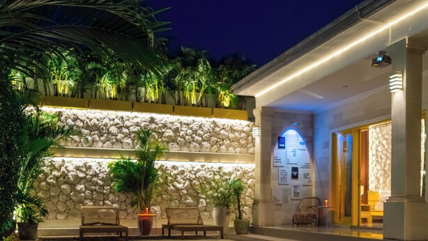 A swimming pool with candles, a stone wall, and lounge chairs. - Villa yellow stone 1 (Kuta utara)