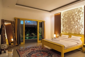 Ein Schlafzimmer mit einem großen Bett, Blick auf einen Pool und einer Glastür.