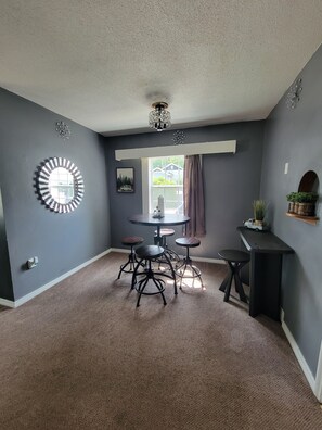 A room with a round table, four stools, a small black table, a window with curtains, and a wall clock. - Canyon Lake GETAWAY 2 bedrooms-1-KING & 1 QUEEN (Rapid City)