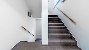 Una escalera moderna con barandilla, una luz fijada a la pared y un radiador.