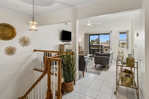 Ein geräumiger Wohnbereich mit Treppe, Fernseher, Esstisch und Blick durch eine Glastür.
