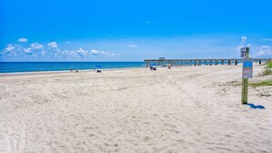 A beach with a pier extending into the ocean, a clear blue sky, and a signpost with the number 31. - 5 Sea Castles - adorable townhouse with limited ocean view (Fernandina Beach)