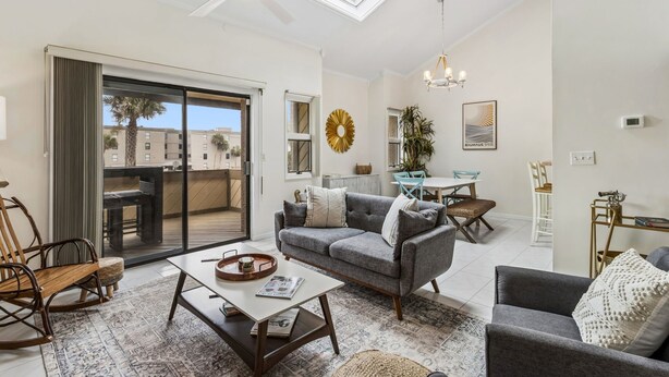 A modern living room with a sofa, coffee table, and a dining area with a table and chairs. - 5 Sea Castles - adorable townhouse with limited ocean view (Fernandina Beach)
