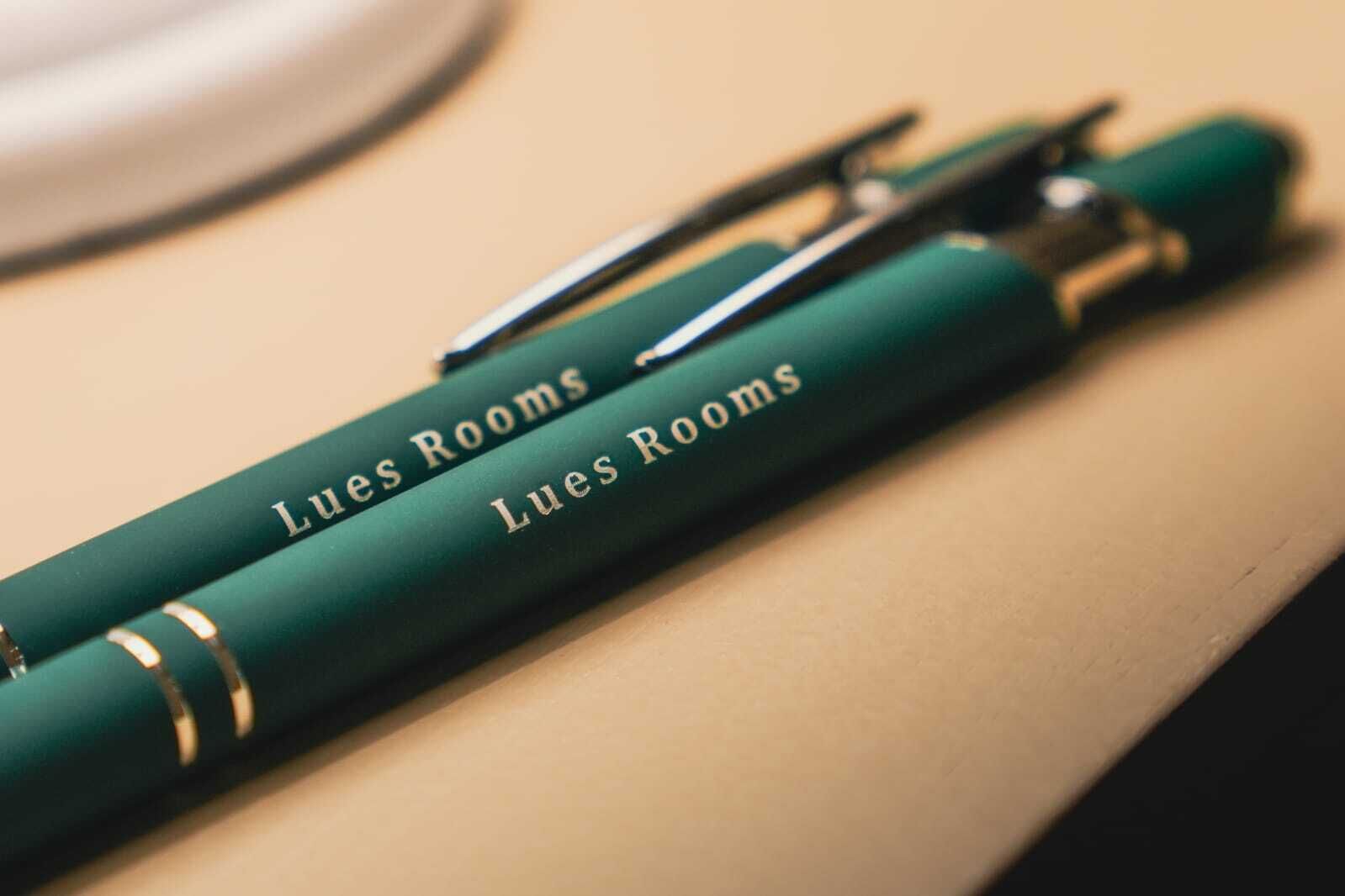 Un bolígrafo verde con la inscripción 'Lues Rooms'.