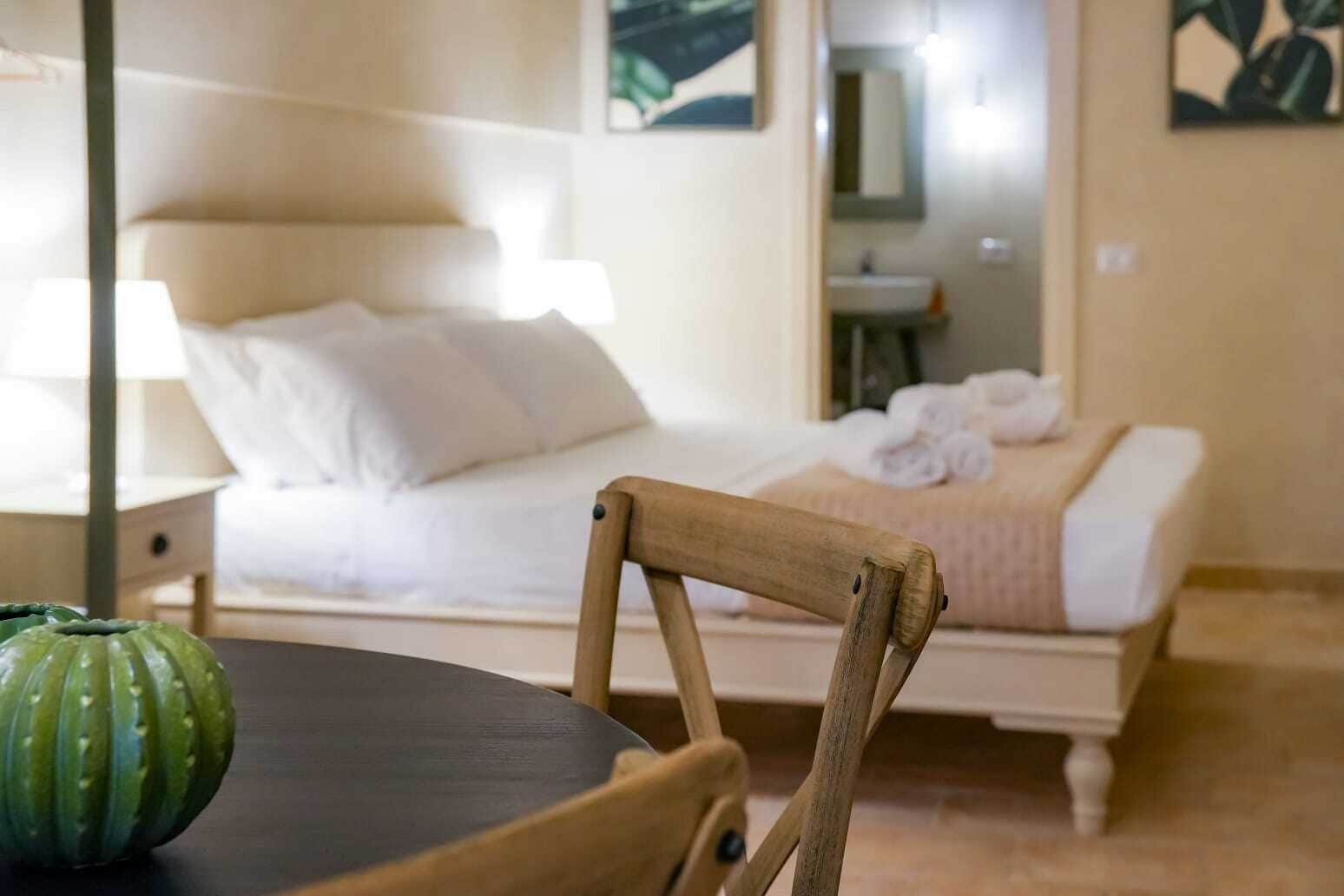 A bedroom with a bed, a bedside table, a chair, and a green object on the table.