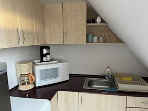 Eine kleine Küche mit Mikrowelle, Kaffeemaschine und Spüle.