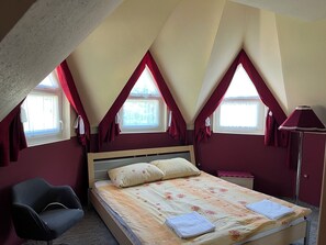 A bedroom with a bed, a chair, a nightstand, and a lamp.