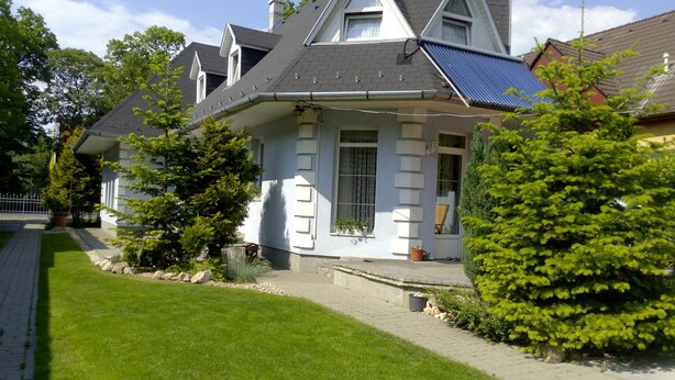 Een woonhuis met een schuin dak, zonnepanelen en een verzorgd gazon.
