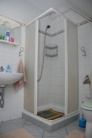 Ein Badezimmer mit Dusche, Waschbecken und Toilette.