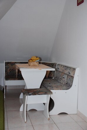 Eine Sitzecke mit Tisch und Bank, eine Obstkorb und ein Fliesenboden.