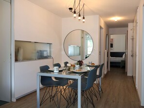 Ein stilvoller Essbereich mit einem runden Spiegel, einem Tisch mit Stühlen und Blick zum Schlafzimmer.