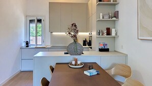 Een moderne keuken met een centraal eiland, inbouwmeubels en een eethoek met een tafel en stoelen.