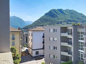 Ein mehrstöckiges Gebäude mit Balkonen, einem Parkplatz und einer Bergkulisse.