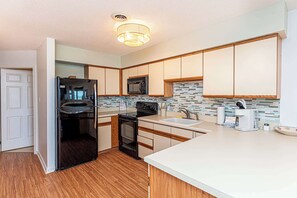 A modern kitchen with a refrigerator, stove, microwave, and sink. - Bayfront 2BR Condo with Water Views (Ocean City)