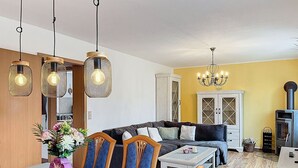 A dining area with a wooden table, chairs, and hanging lights. - Stunning private villa for 6 guests with WIFI, TV, patio and panoramic view (Greifswald)