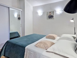 Ein Schlafzimmer mit Bett, Kissen, einer Nachttischlampe, einem Spiegel und Wandleuchten.