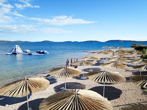 Ein Strand mit klarem, blauem Wasser, einem kleinen Boot und Strandkörben.