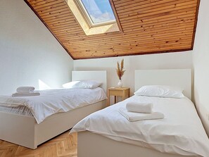 Ein Schlafzimmer mit zwei Betten, einem Oberlicht und einer Holzbalkendecke.