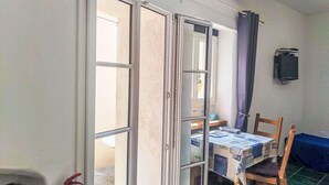 A room with a sliding glass door leading to an outdoor area, a table with boxes, a chair, a fire extinguisher, and a wall-mounted television. - Beautiful private villa for 2 people with WIFI and terrace (Cipressa)