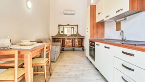 Eine kleine Küche mit Holzschränken, einem Esstisch mit Stühlen und einem großen Spiegel darüber.
