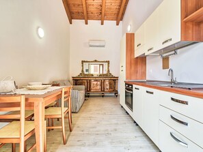 Eine kleine Küche mit Holzschränken, einem Esstisch mit Stühlen und einem großen Spiegel darüber.