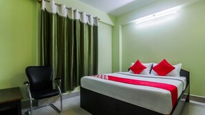 Une chambre d’hôtel avec un lit, une chaise, une table et des rideaux.