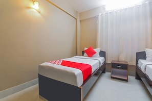 A hotel room with a bed, a nightstand, and a window with curtains.