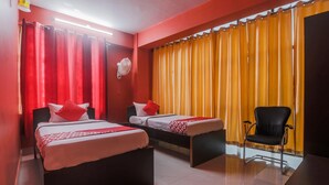 Une chambre d’hôtel avec deux lits, une chaise, un bureau et un ventilateur.