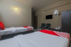 A hotel room with two beds, a desk, a chair, a TV, and a wall-mounted fan. - Classic Solace Residency (Shillong)