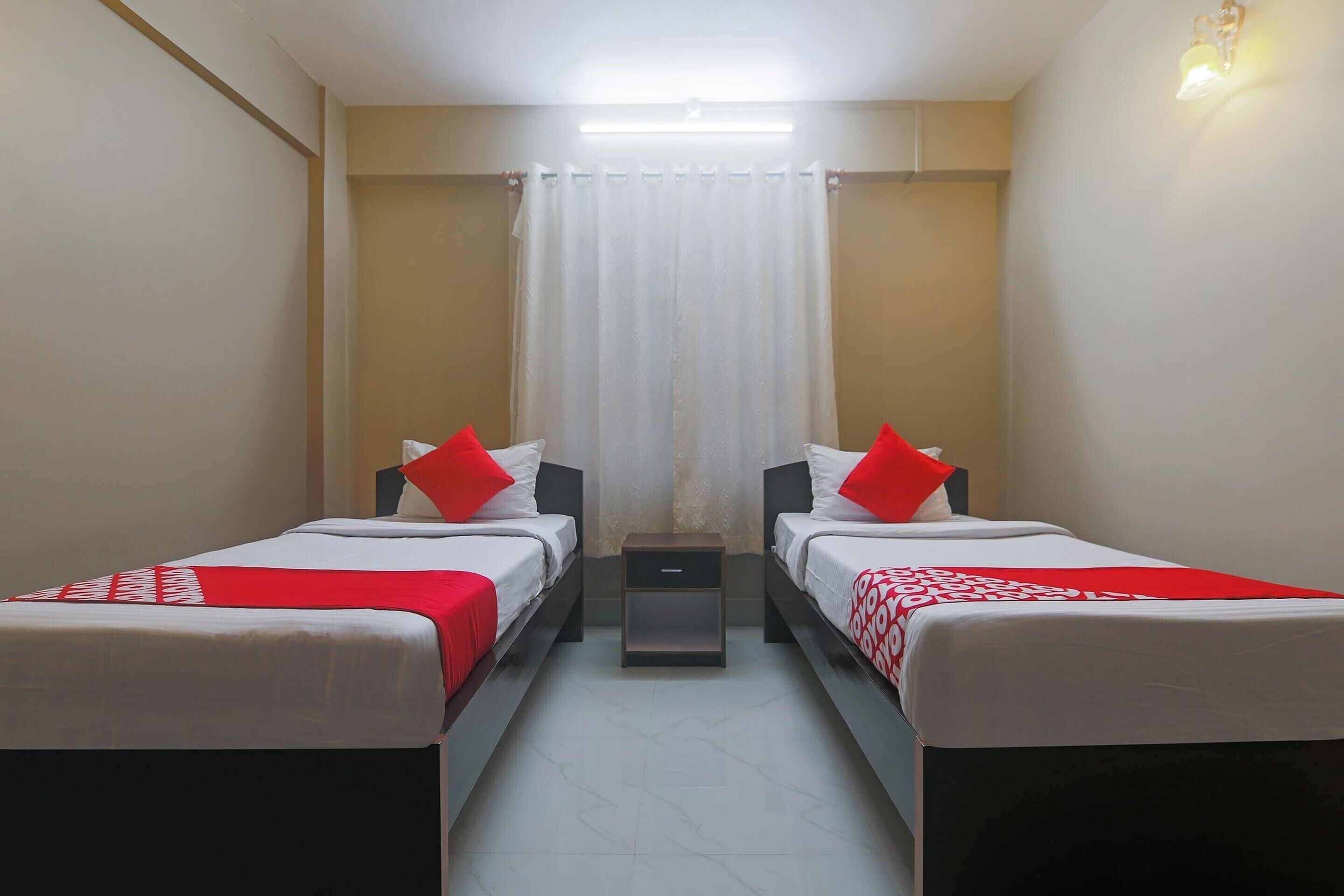 Une chambre double avec deux lits, une table de chevet et un rideau.
