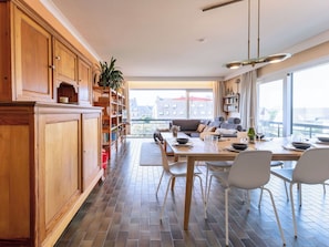Eine moderne Küche mit Holzausstattung, ein Essbereich mit Tisch für zwei Personen und Blick auf die Stadt durch große Fenster.