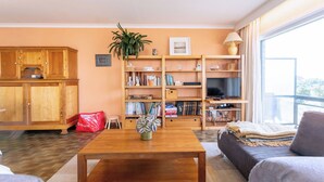 Een woonkamer met een houten salontafel, een bank, een televisie en een boekenkast.