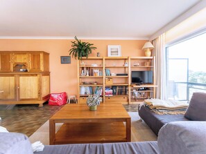 Ein Wohnzimmer mit Couch, Fernseher, Bücherregal und Couchtisch.