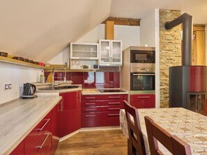 A kitchen with red cabinets, a wooden countertop, a built-in oven, and a stone wall. - Stunning  villa for 6 people with WIFI and TV (Jilemnice)