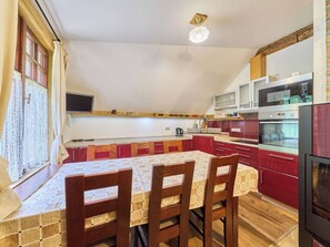 A kitchen with a dining table, chairs, a TV, and red cabinets. - Stunning  villa for 6 guests with WIFI and TV (Jilemnice)