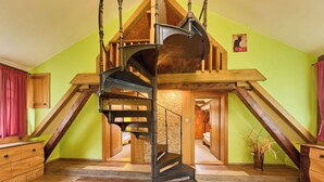 Escadaria em espiral em um quarto com vigas de madeira e parede verde.