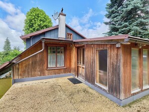 Eine Holzhütte mit geneigtem Dach, Schornstein und einem Kiesweg.