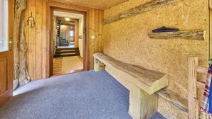 Um quarto com um banco de madeira, uma parede de pedra e uma porta de madeira.