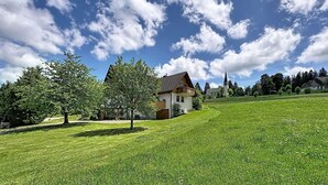 A rural landscape with a house, a church, and a grassy field. - Cosy apartment for 2 guests with WIFI, TV and patio (Loch)