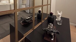 Ein Zimmer mit einem großen Spiegel, der ein Bett und ein Fenster mit Vorhängen reflektiert.