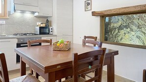 Eine moderne Küche mit weißen Schränken, einem Gasherd, einer Mikrowelle und einem Essbereich mit Holztisch und Stühlen.